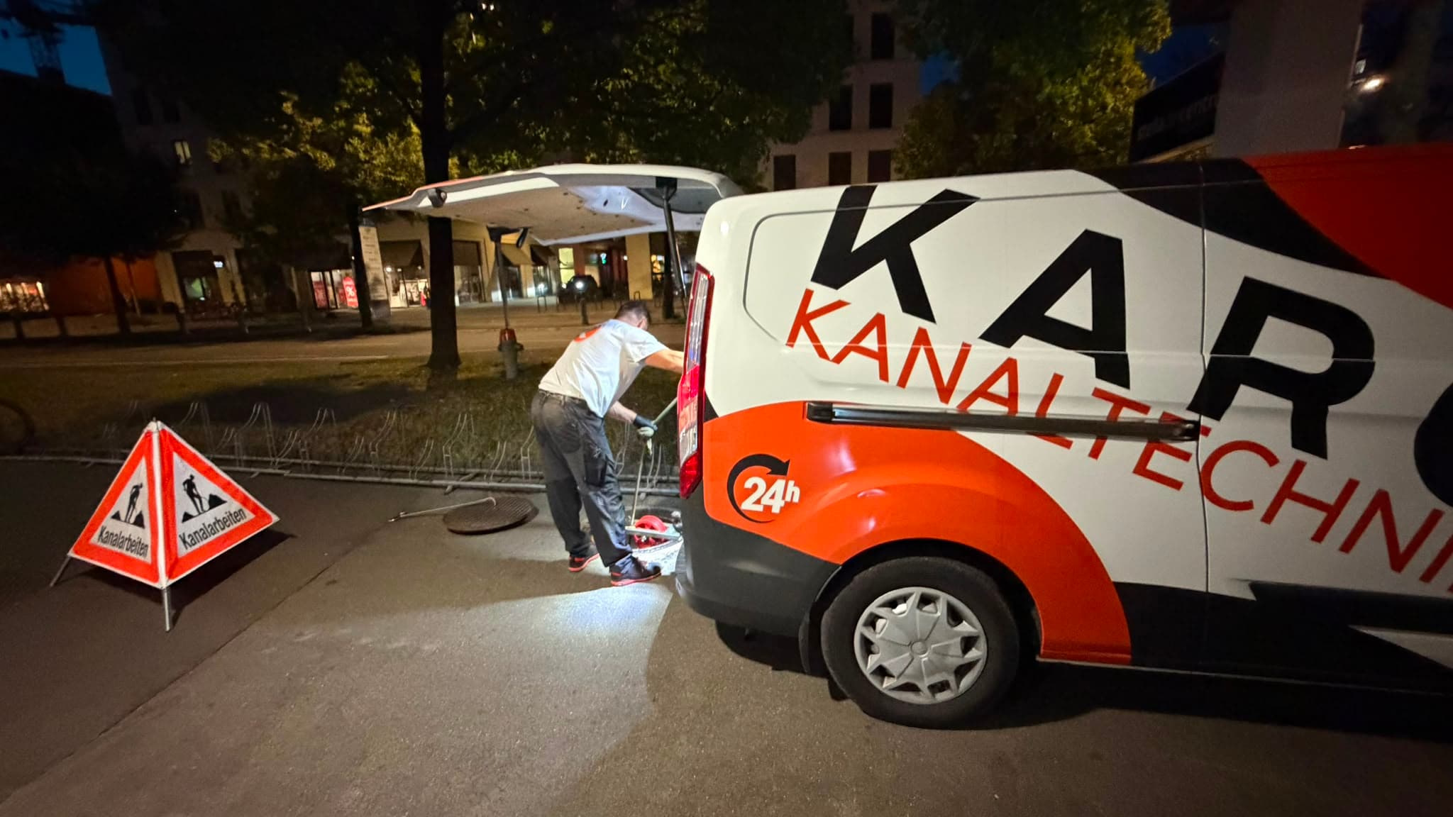 Techniker zieht nachts die Spülleitung aus dem Strassenschacht