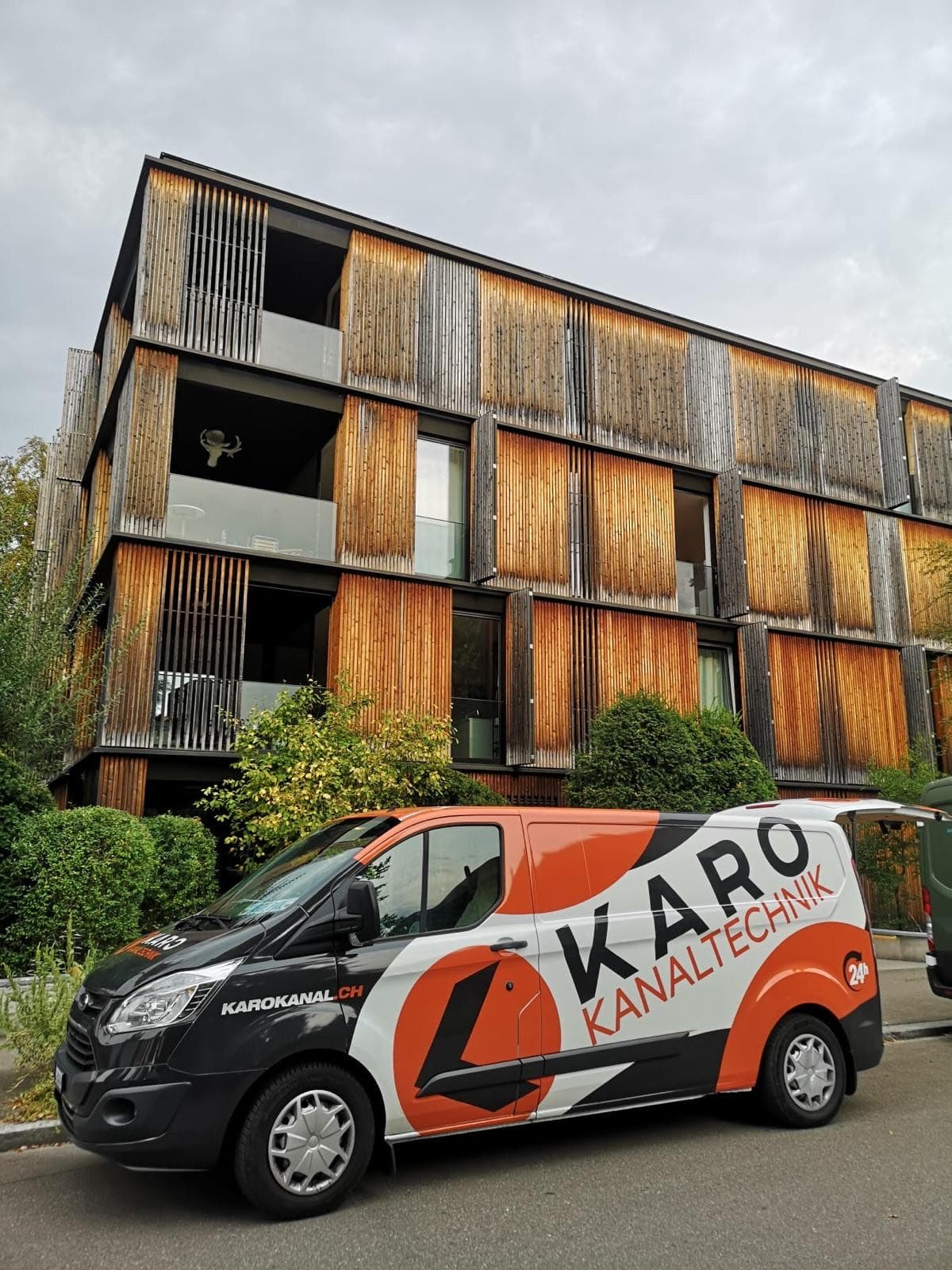 Einsatzfahrzeug von Karo Kanaltechnik vor einem modernen Wohnhaus mit Holzfassade