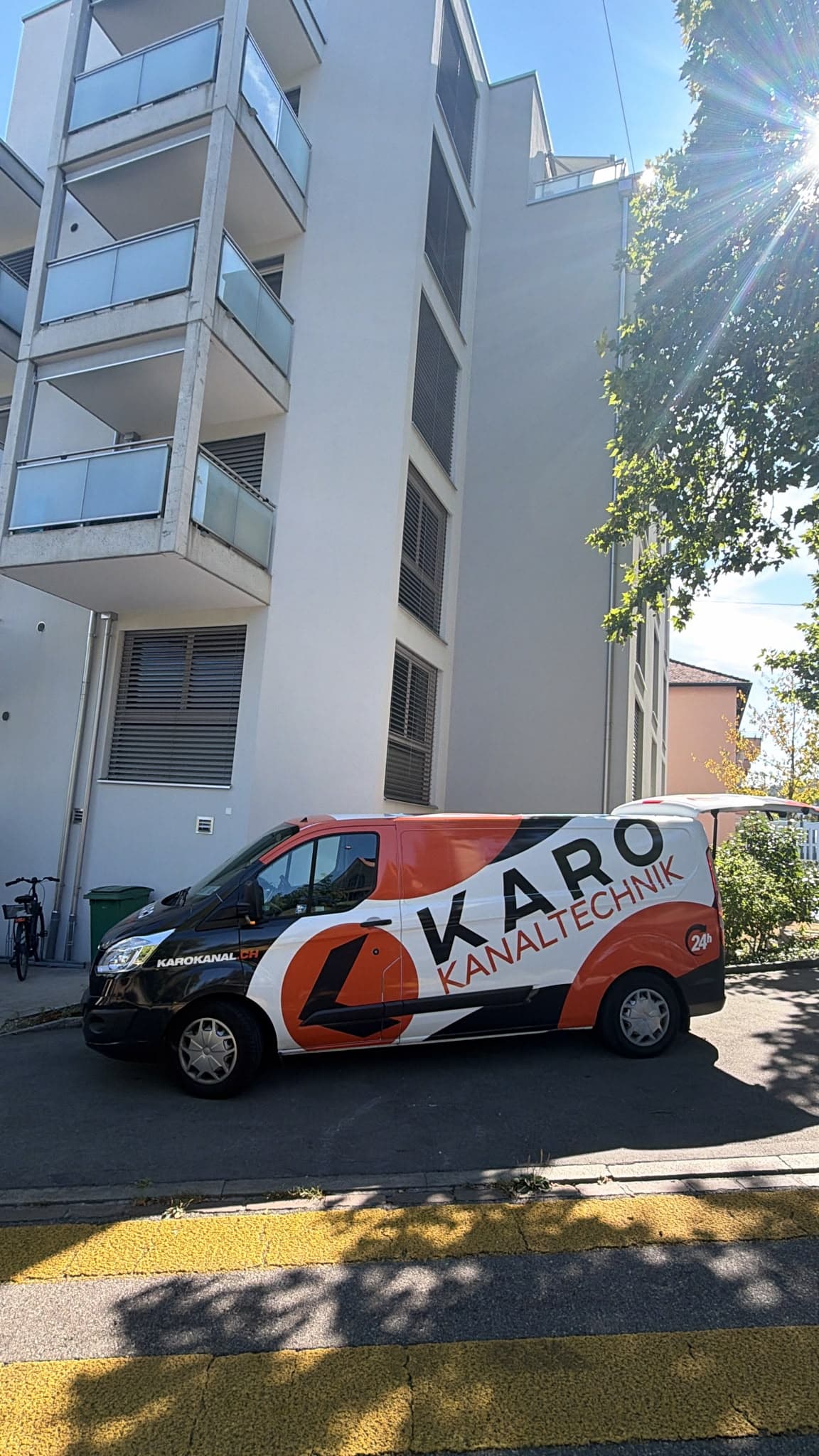 Einsatzfahrzeug von Karo Kanaltechnik vor einem Wohnhaus mit Garten an einem Sommertag